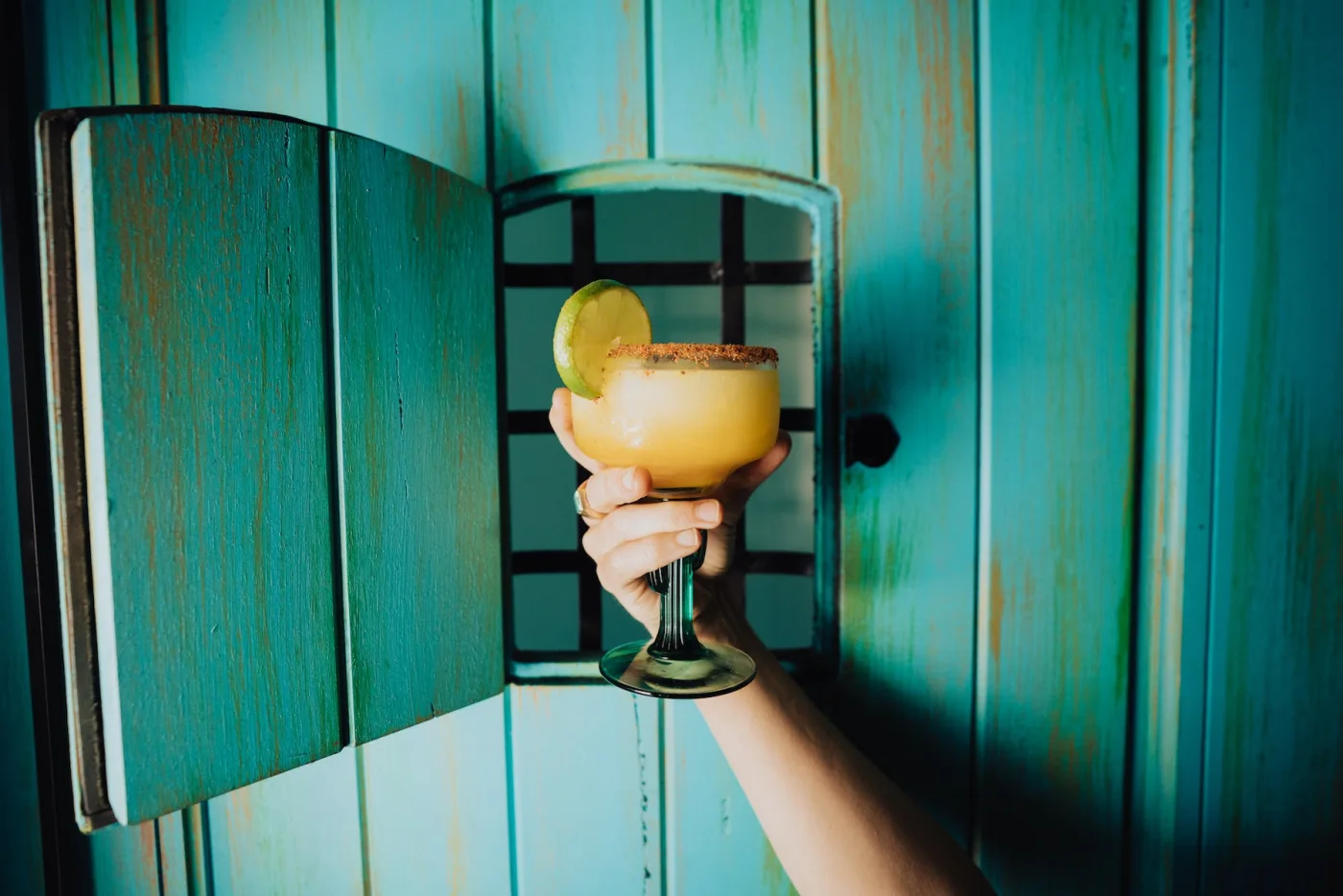 A LUNA cocktail held in front of the restaurant’s turquoise door