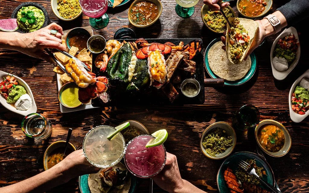 Friends sharing a table filled with LUNA food and drinks